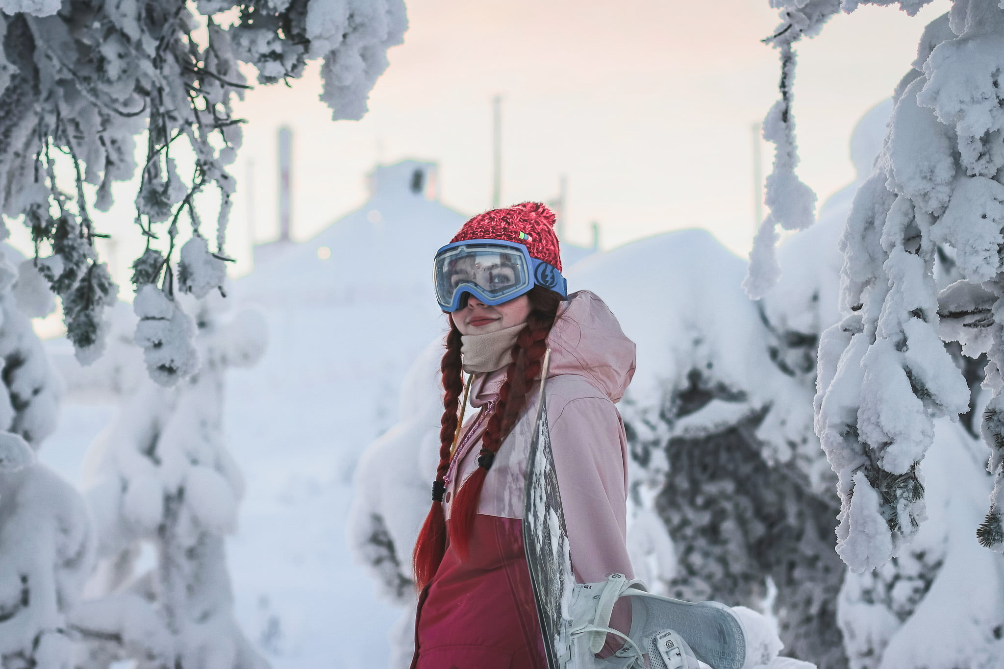 Ung kvinne med snowboard i vinterlandskap.