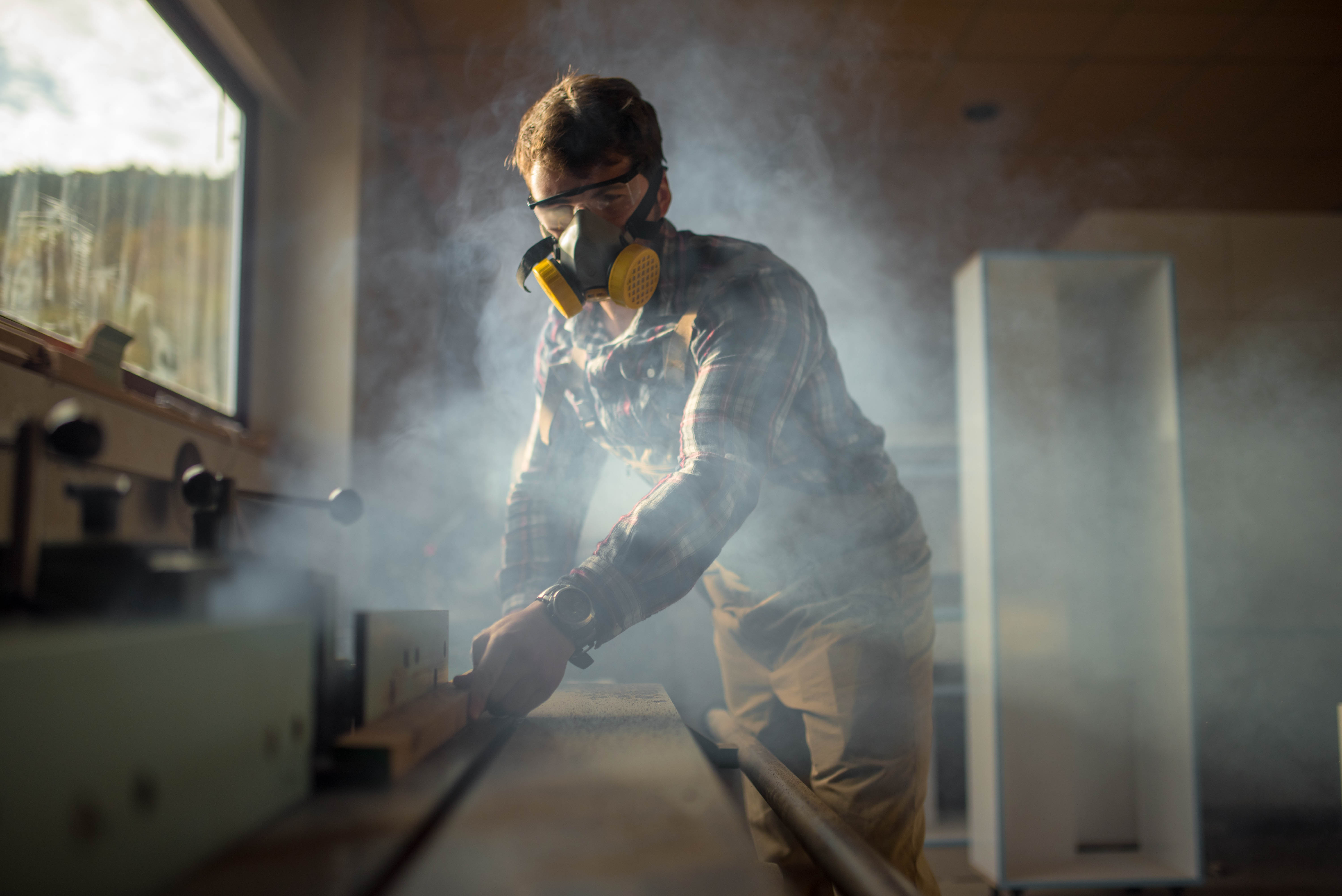 Håndverker som høvler i verkstedet sitt